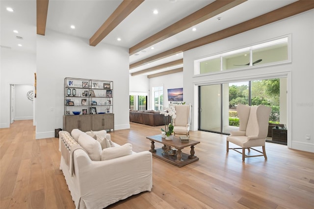 living room featuring a wealth of natural light, light wood-type flooring, and beam ceiling