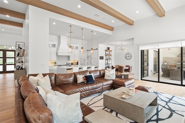 living room featuring beam ceiling, an inviting chandelier, and light hardwood / wood-style floors