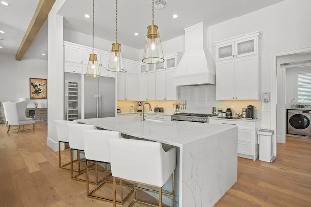 kitchen with light hardwood / wood-style flooring, washer / dryer, beam ceiling, and custom range hood