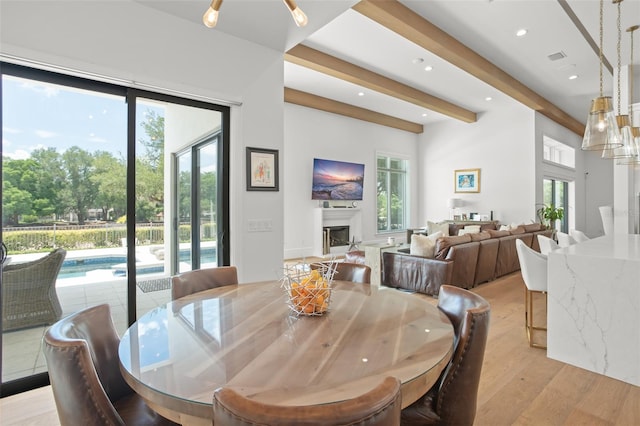 dining room with plenty of natural light, beamed ceiling, and light hardwood / wood-style floors