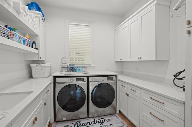 laundry area with cabinets, washer and clothes dryer, sink, and hardwood / wood-style flooring