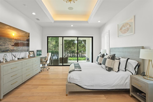 bedroom with light hardwood / wood-style flooring, a raised ceiling, and access to outside