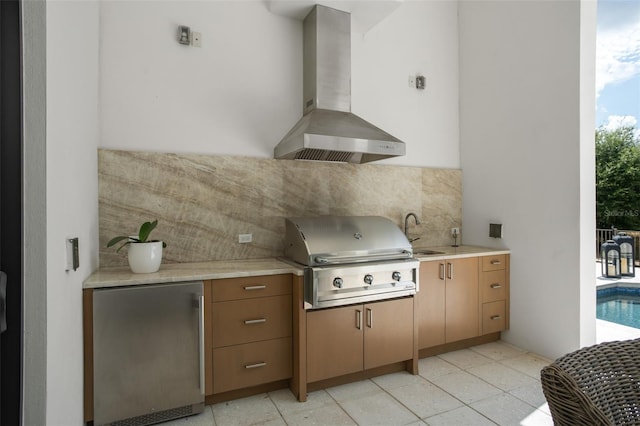 kitchen with stainless steel fridge, plenty of natural light, sink, and wall chimney range hood