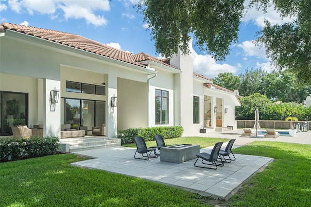 back of house with a fire pit, a patio area, a lawn, and a pool