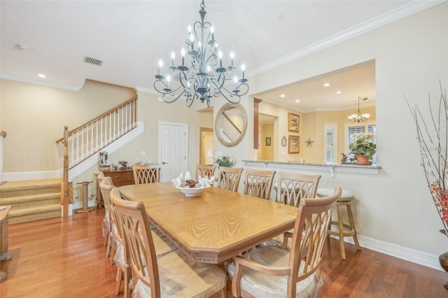 dining area featuring crown molding, an inviting chandelier, and hardwood / wood-style flooring