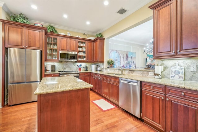 kitchen featuring sink, stainless steel appliances, a center island, crown molding, and light hardwood / wood-style floors