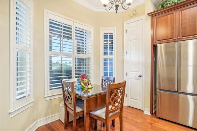 dining space featuring light wood-type flooring, crown molding, and a chandelier