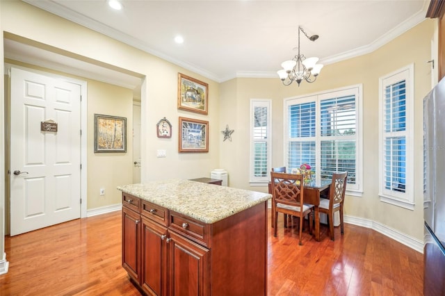 kitchen featuring hardwood / wood-style flooring, crown molding, an inviting chandelier, and decorative light fixtures