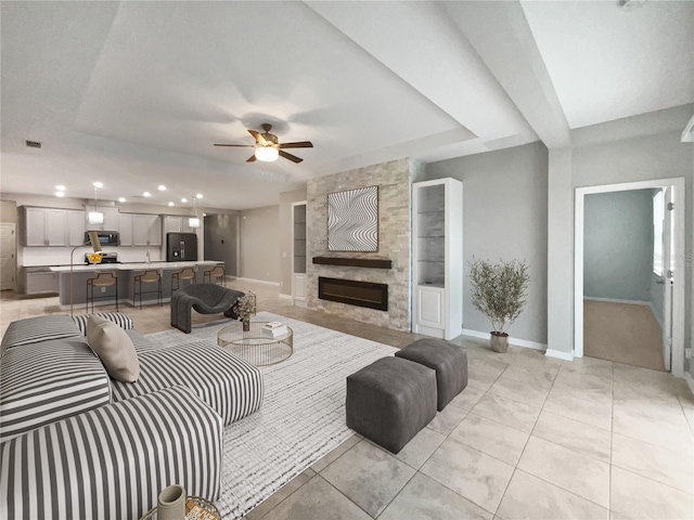 tiled living room featuring built in features, a large fireplace, and ceiling fan