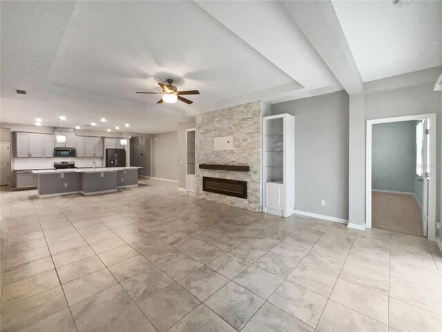 unfurnished living room featuring built in features, ceiling fan, light tile patterned floors, and a fireplace