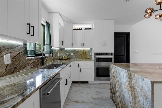 kitchen featuring stainless steel appliances, light stone counters, backsplash, and white cabinetry