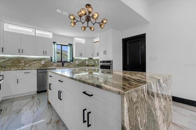 kitchen with a kitchen island, tasteful backsplash, stainless steel appliances, light stone counters, and white cabinets