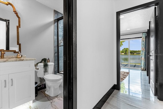 bathroom with a textured ceiling, vanity, toilet, and a healthy amount of sunlight