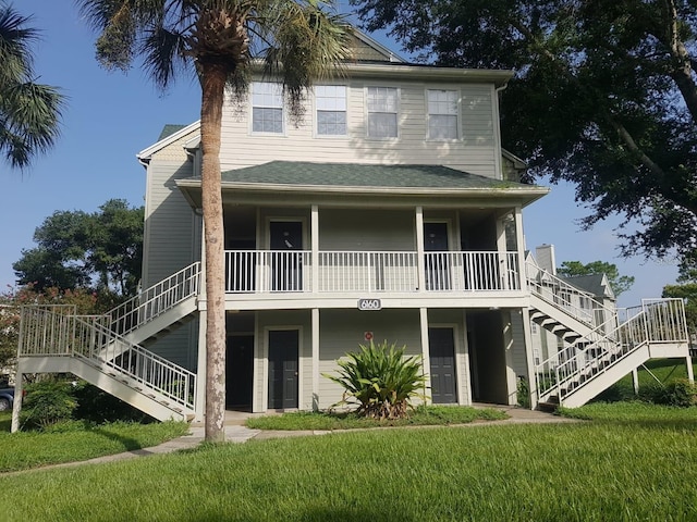 rear view of property featuring a garage, a porch, and a yard