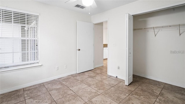 unfurnished bedroom with light tile patterned floors, ceiling fan, and a closet