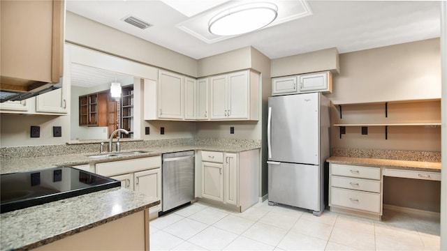 kitchen with light stone countertops, appliances with stainless steel finishes, sink, and light tile patterned floors