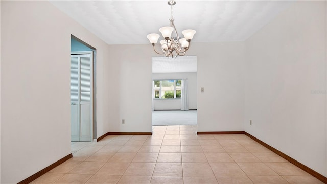 tiled empty room featuring a notable chandelier