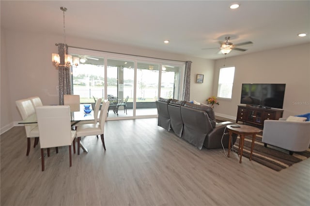 living room featuring ceiling fan with notable chandelier and light hardwood / wood-style floors