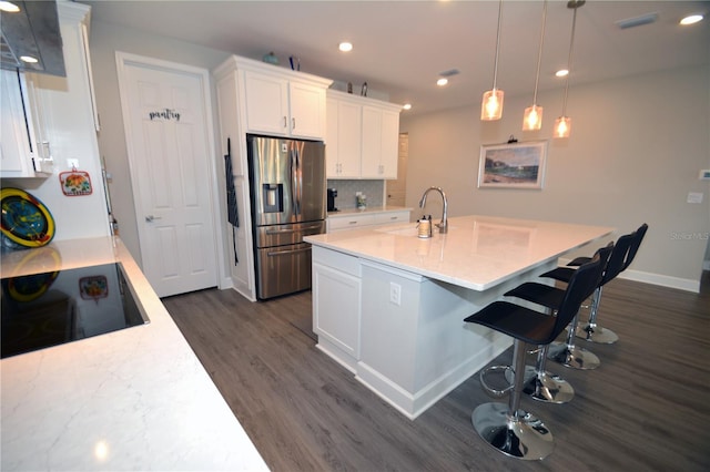 kitchen featuring pendant lighting, stainless steel fridge with ice dispenser, sink, white cabinetry, and black electric cooktop