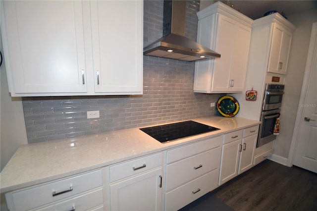 kitchen featuring white cabinetry, tasteful backsplash, dark hardwood / wood-style floors, wall chimney exhaust hood, and black electric cooktop