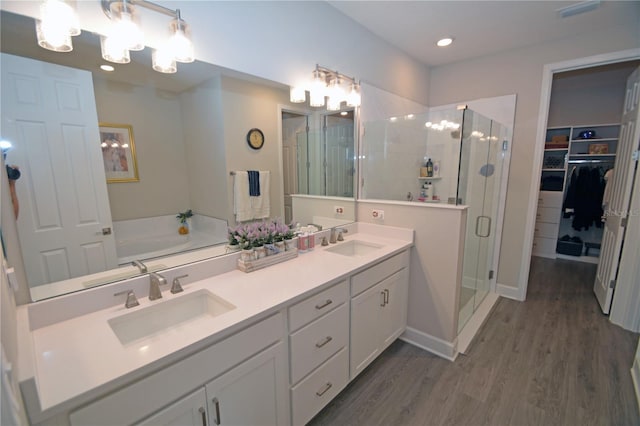 bathroom with wood-type flooring, shower with separate bathtub, and vanity