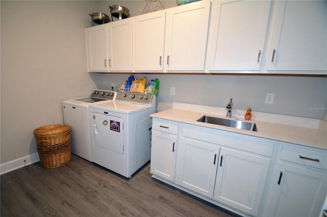 clothes washing area featuring dark hardwood / wood-style floors, sink, cabinets, and washing machine and dryer