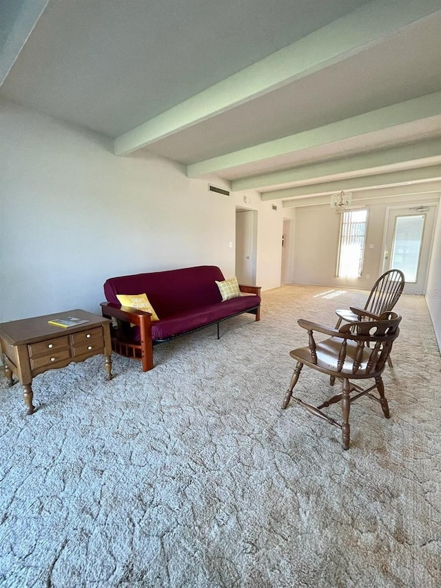 living room featuring beamed ceiling, carpet flooring, and a notable chandelier