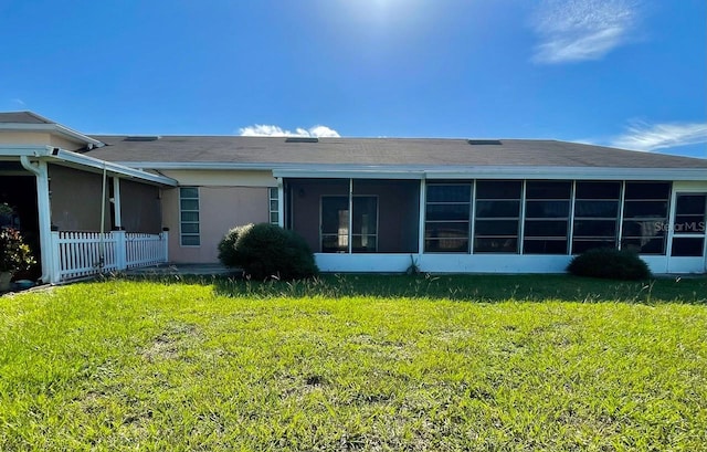 back of property with a yard, a sunroom, and stucco siding