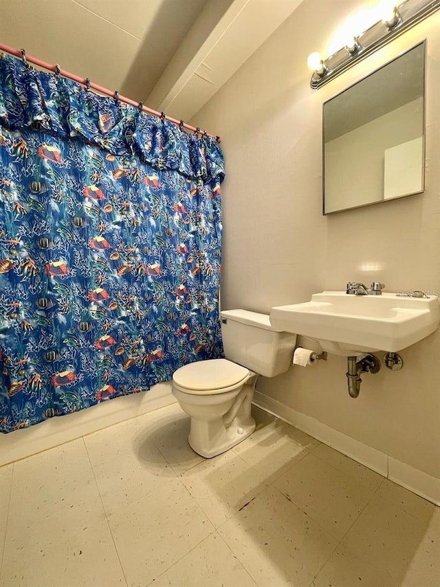 full bath featuring a shower with shower curtain, baseboards, a sink, tile patterned flooring, and toilet