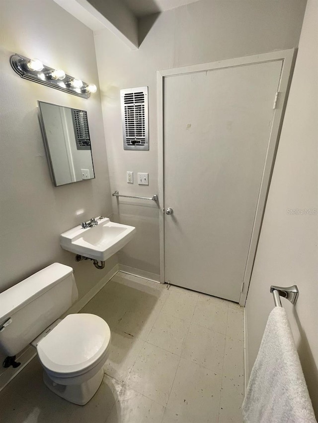 half bath featuring tile patterned floors, visible vents, toilet, and a sink