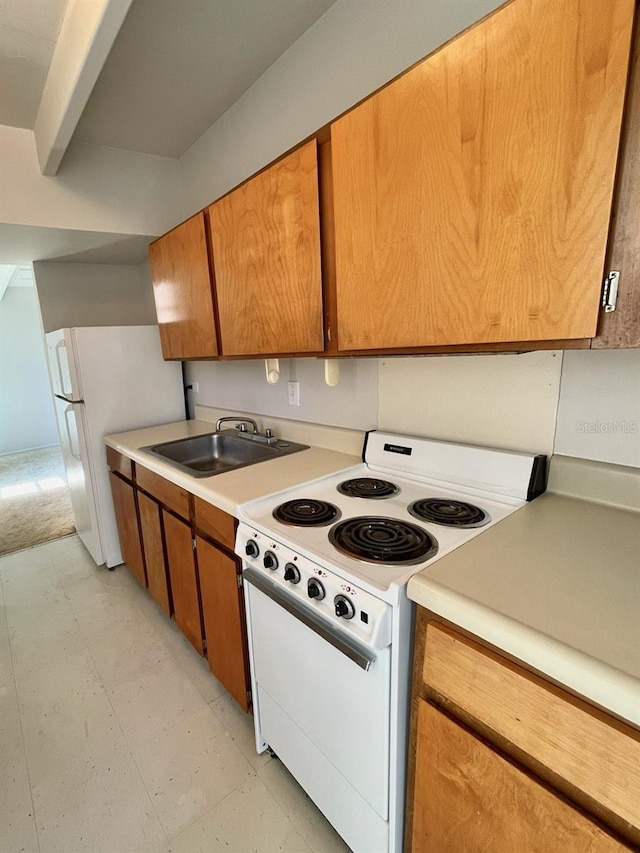 kitchen featuring light floors, white appliances, light countertops, and a sink