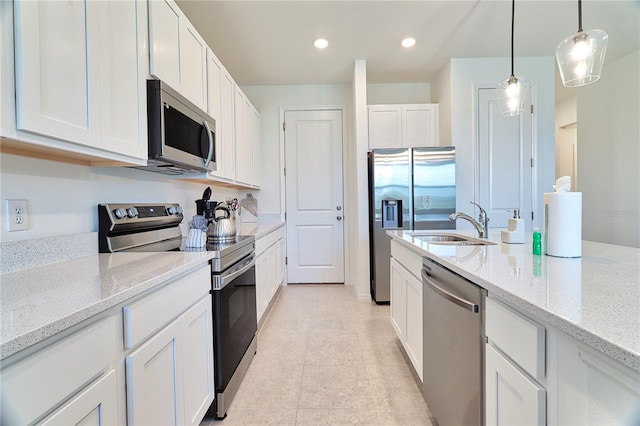 kitchen featuring light tile patterned floors, appliances with stainless steel finishes, light stone counters, white cabinetry, and sink