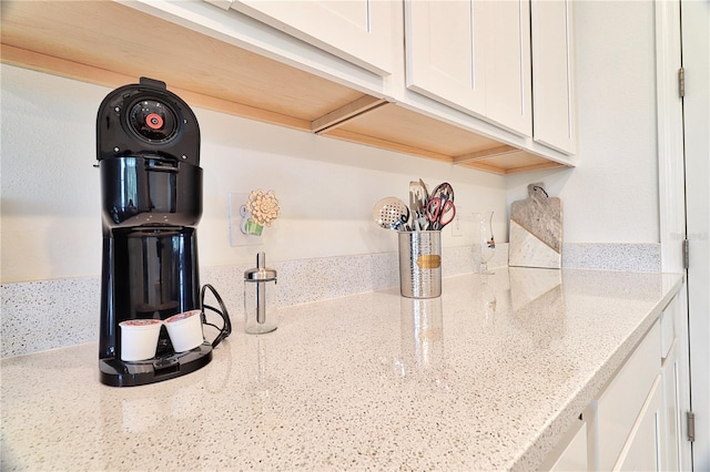 room details featuring white cabinets and light stone countertops