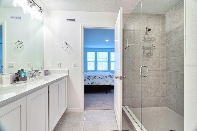 bathroom featuring tile patterned flooring, a shower with door, a textured ceiling, and vanity