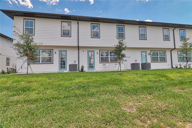 back of property featuring cooling unit and a lawn