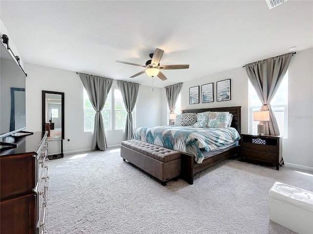 bedroom featuring ceiling fan, light colored carpet, and a barn door