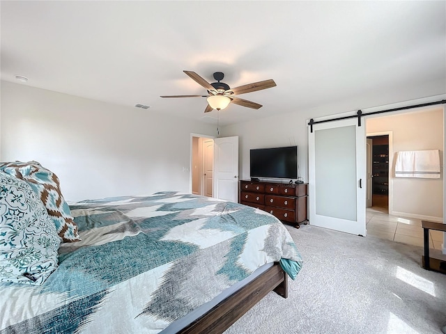 carpeted bedroom featuring ceiling fan and a barn door