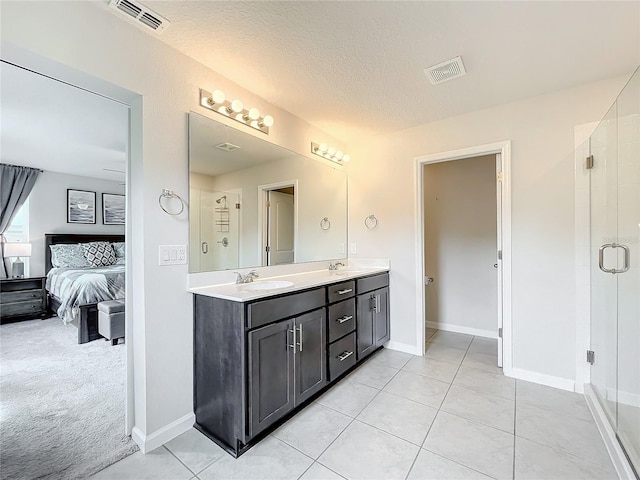 bathroom with an enclosed shower, vanity, tile patterned flooring, and a textured ceiling