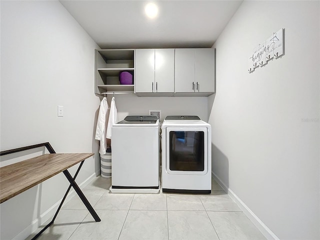 clothes washing area with cabinets, separate washer and dryer, and light tile patterned flooring