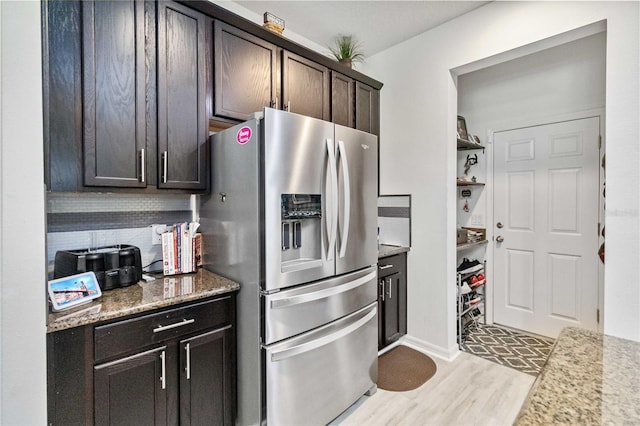 kitchen with light stone counters, dark brown cabinets, light hardwood / wood-style floors, and stainless steel refrigerator with ice dispenser