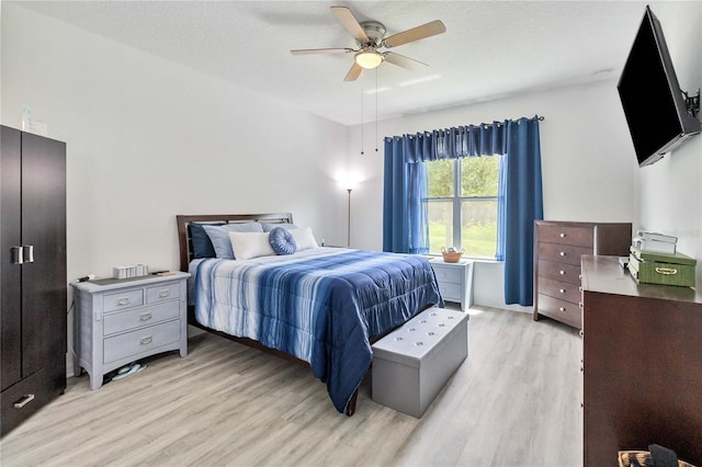 bedroom with a textured ceiling, ceiling fan, and light wood-type flooring