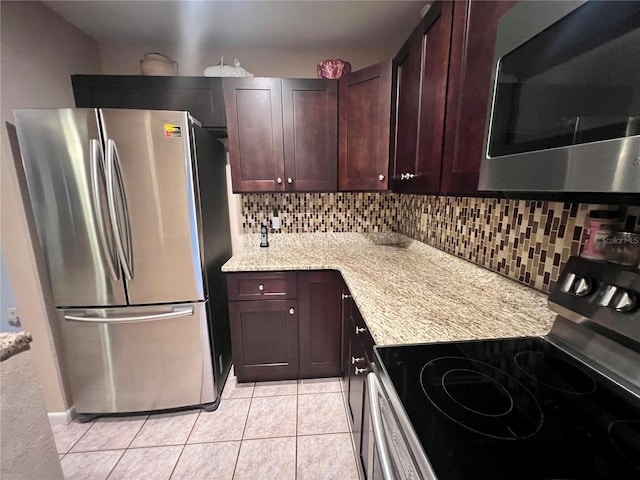 kitchen with stainless steel appliances, light stone counters, light tile patterned floors, and tasteful backsplash