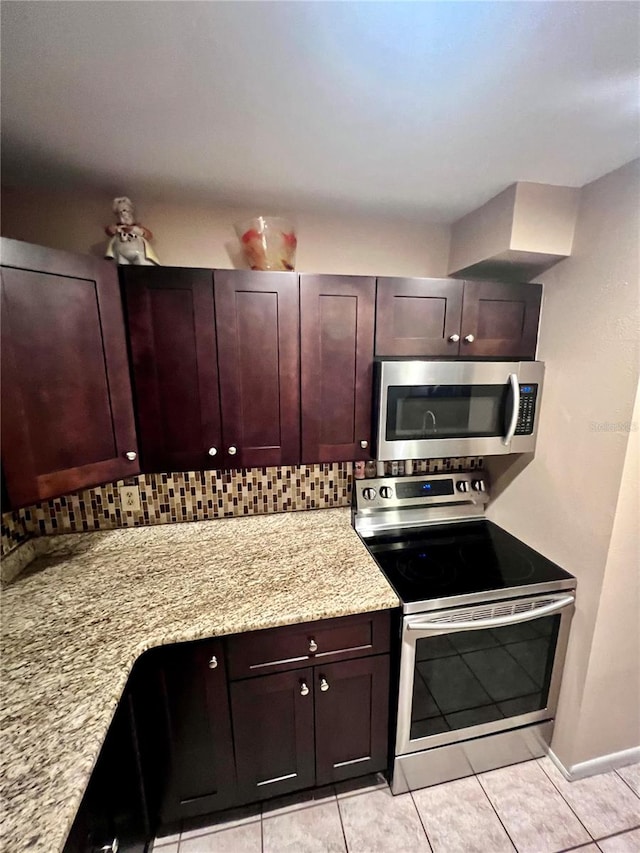 kitchen featuring light stone counters, stainless steel appliances, tasteful backsplash, and light tile patterned flooring