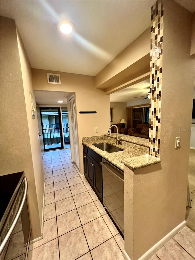 kitchen with light stone countertops, light tile patterned floors, stainless steel appliances, sink, and ceiling fan