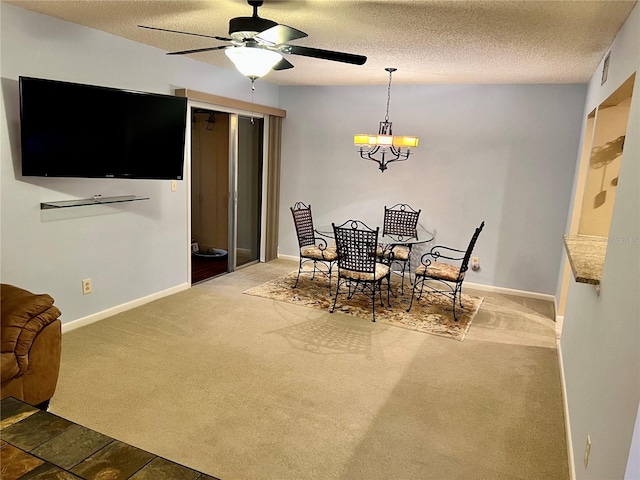 dining room featuring ceiling fan with notable chandelier, a textured ceiling, and dark colored carpet