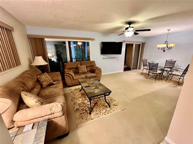 living room featuring a textured ceiling, light colored carpet, and ceiling fan with notable chandelier