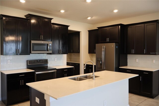 kitchen featuring appliances with stainless steel finishes, tasteful backsplash, a center island with sink, and sink