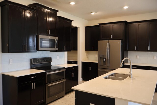 kitchen with appliances with stainless steel finishes, backsplash, an island with sink, and sink