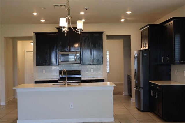 kitchen with an island with sink, stainless steel appliances, sink, and an inviting chandelier