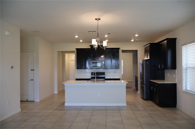 kitchen featuring a kitchen island with sink, appliances with stainless steel finishes, a chandelier, and sink